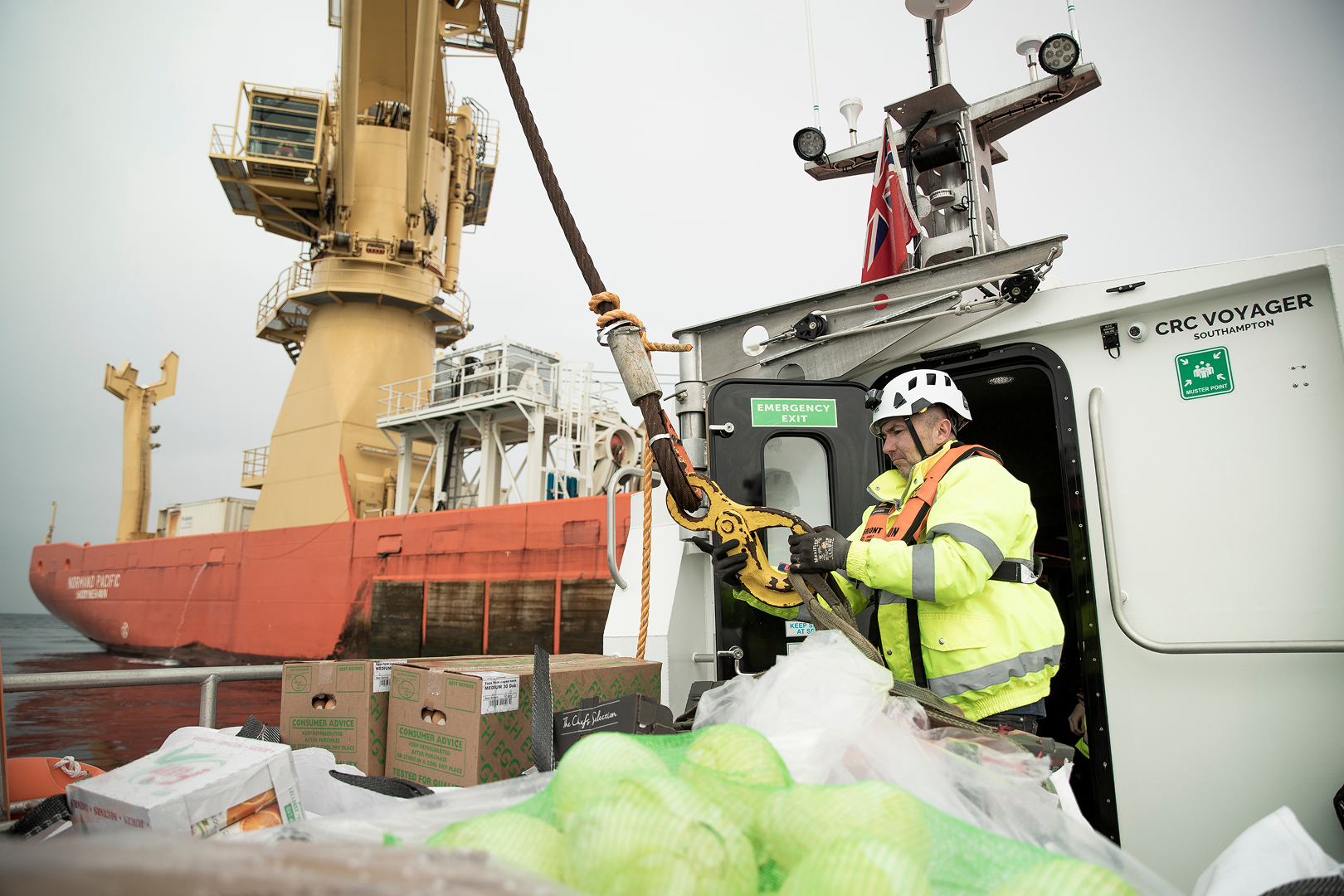 Commercial RIB charter supporting offshore logistics with crew transferring supplies between vessels at sea.