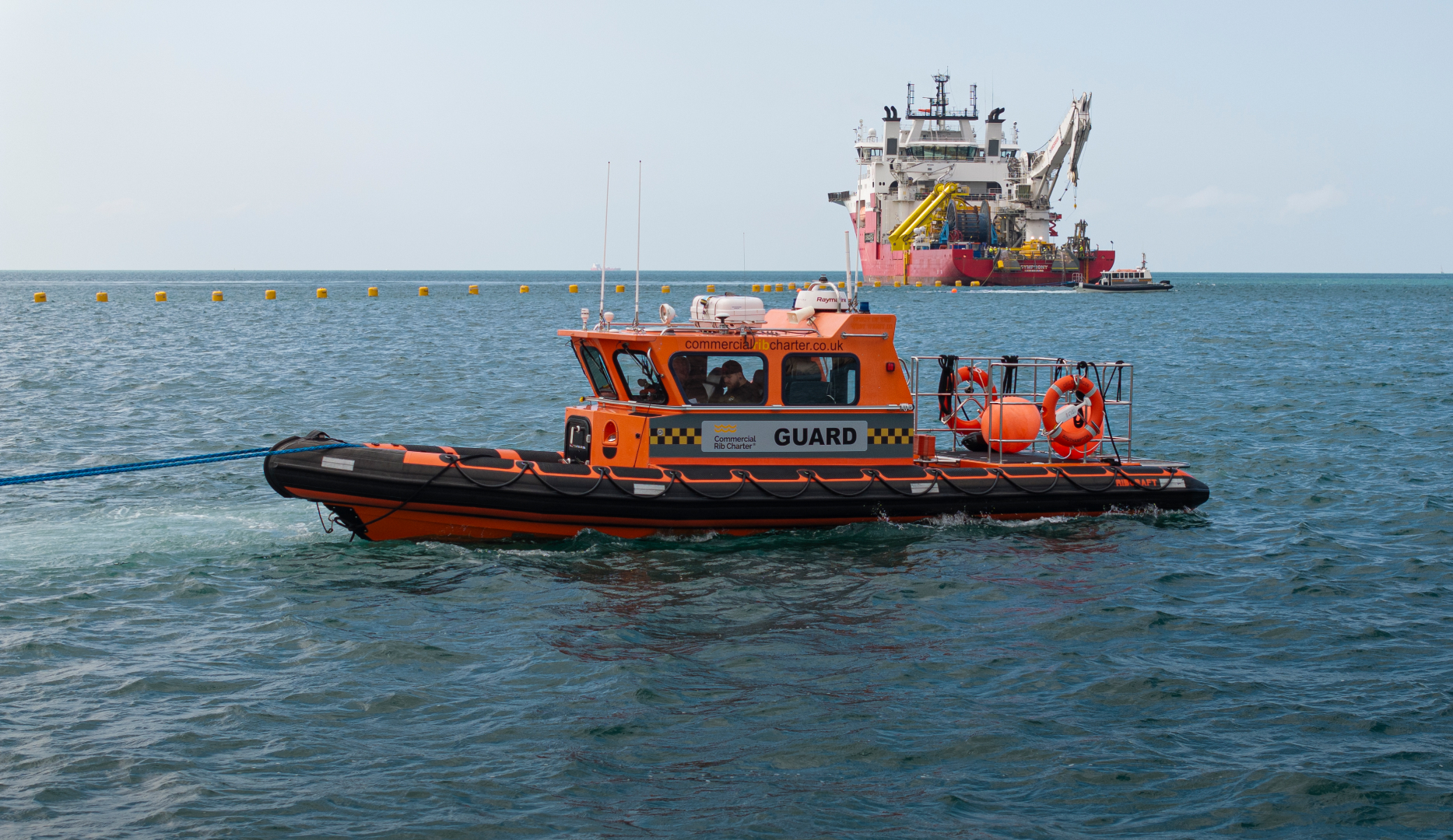 Commercial RIB charter guard vessel providing offshore safety support near construction and installation vessel at sea