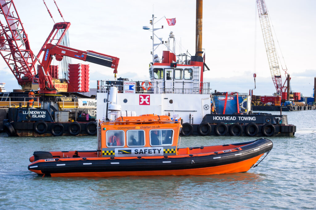 Commercial RIB charter safety boat operating alongside offshore construction vessel during marine works in the UK